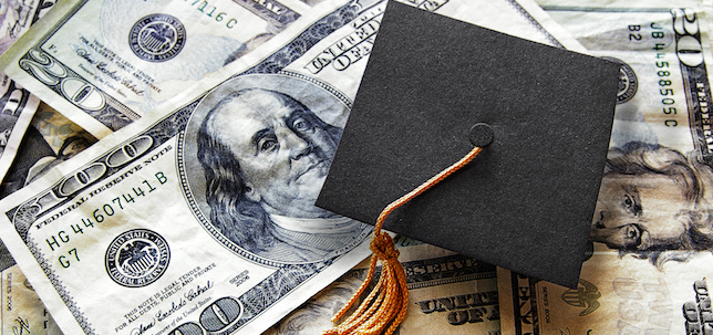 pile of dollar bills with graduation cap